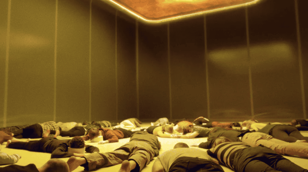 The semi-mysterious Artilect known as the Mima glows bright orange and yellow above a group of passengers lying on the floor of the Mima Hall. Desperate to escape their fate aboard the Aniara any way they can, the humans attempt to find solace in visions from their past on Earth brought up by the Mima.